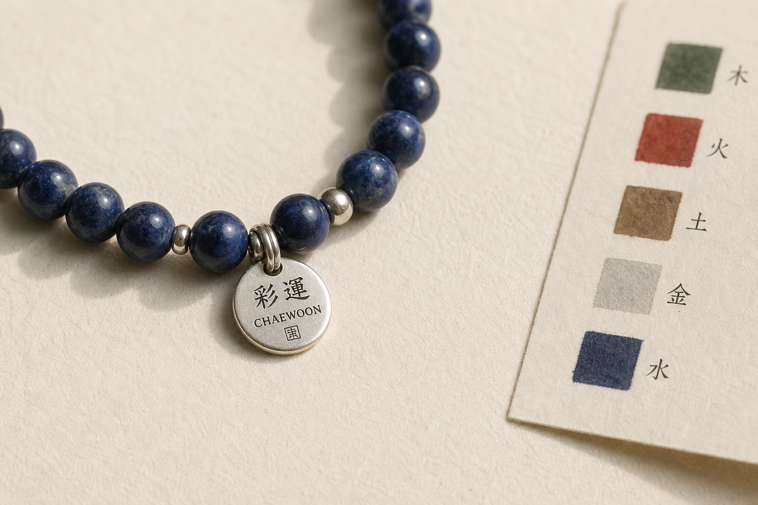 채운 팔찌 close-up — 깊은 청 천연 원석과 925 silver charm, 옆에 다섯 결의 색 swatch